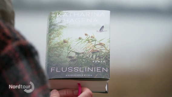 Ein Buch mit dem Titel "Flusslinien" wird von einer Person in die Kamera gehalten. © Screenshot 