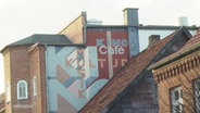 Eine bunt bemalte Häuserfassade mit den Schriftzügen "Kino", "Cafe", "Kultur", "Musik". © Screenshot 