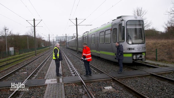 Drei Männer stehen neben einer Straßenbahn. © Screenshot 