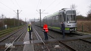 Drei Männer stehen neben einer Straßenbahn. © Screenshot 