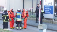 Einsatzkräfte der Feuerwehr tragen Schutzanzüge. © Screenshot 