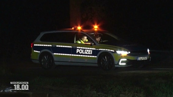 Zwei Polizisten sitzen in ihrem Dienstwagen auf einer dunklen Straße. © Screenshot 