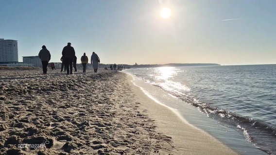 Menschen gehen am Strand spazieren. © Screenshot 