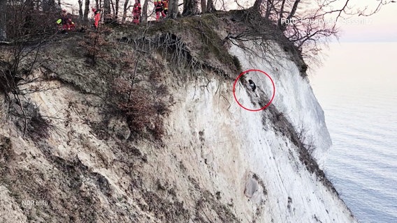 An der Rügener Steilküste hängt eine junge Frau an den Klippen. Sie ist in der Ferne schwer zu erkennen und daher rot eingekreist. © Screenshot 