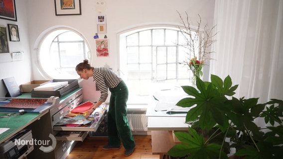 Papierkünstlerin Martha von Maydell öffnet in Ihrem Atelier eine Schublade mit buntem Papier. © Screenshot 