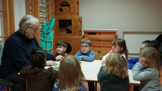 Eine Frau sitzt mit Kindern zusammen an einem Tisch. © Screenshot 