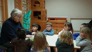 Eine Frau sitzt mit Kindern zusammen an einem Tisch. © Screenshot 