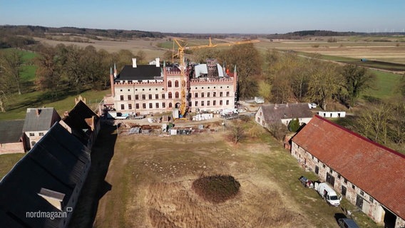 Blick auf eine Schlossanlage auf dem Land deren Haupthaus augenscheinlich restauriert wird. © Screenshot 