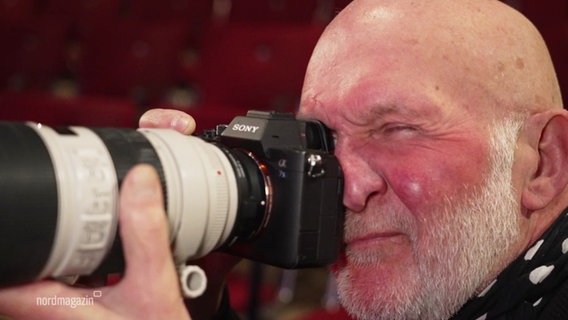 Fotograf Geert Maciejewski kneift sein Auge beim Blick durch eine Fotokamera zu. © Screenshot 