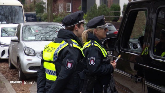 Polizeibeamtinnen klären einen Vater darüber auf, warum er seine Tochter besser nicht mit dem Auto zur Schule bringen soll. © Screenshot 