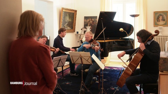 Heikedine Körting lauscht dem Musiker David Stromberg am Duplex-Piano und seinen Musiker Kollegen an ihren Streichinstrumente. © Screenshot 