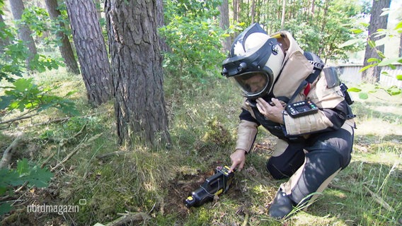 Ein Mitarbeiter des Munitionsbergungsdienstes trägt einen Schutzanzug.  