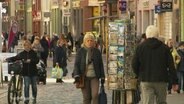 Passanten flanieren in einer Fußgängrzone 