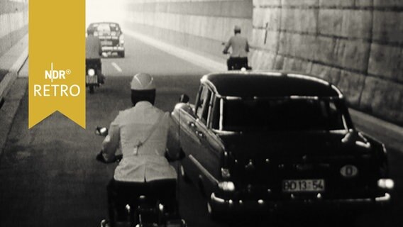 Zwei Oldtimer und zwei Mopeds auf dem Weg zum Tunnelausgang  