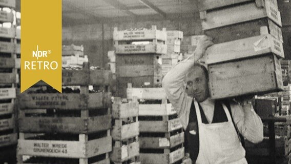Händler trägt Paletten in einem Lager für Obst (1958)  
