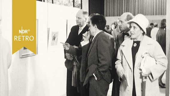 Eine Gruppe Menschen betrachtet ein Gemälde in einer Ausstellung.  