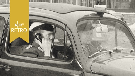 Polizist telefoniert im Polizeiwagen (1960)  