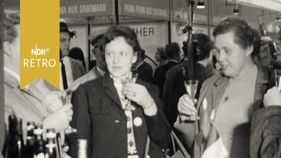 Frauen verkosten Wein an einem Messestand (1965)  