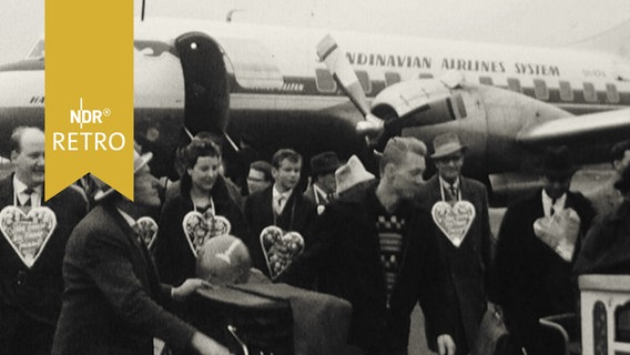 Passagiere aus Kopenhagen am Bremer Flughafen während des Freimarktes 1961 mit Lebkuchenherzen dekoriert  