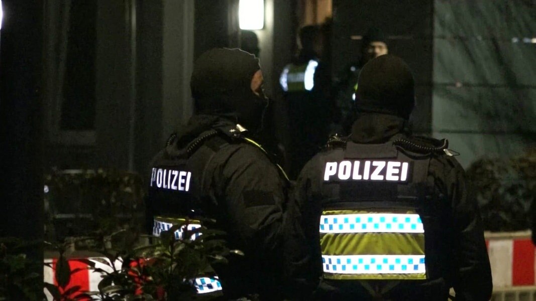 Zwei Polizisten stehen vor einem Haus an der Cuxhavener Straße.
