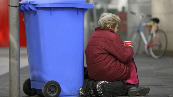 Eine Bettlerin sitzt vor einer Mülltonne auf der Straße © dpa-Report Foto: Uwe Anspach