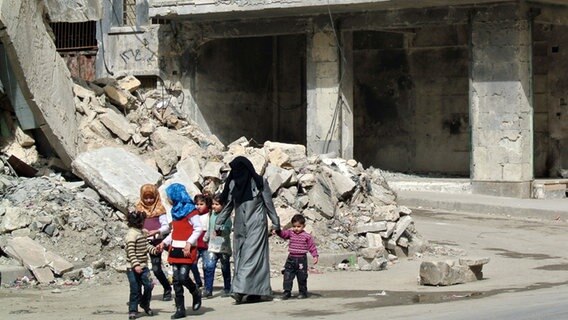 Eine Familie läuft durch die Trümmer der syrischen Stadt Aleppo © picture alliance / abaca Foto: Ammar Abd Rabbo