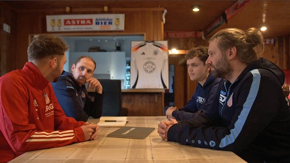 Vier Männer sitzen an einem Wirtshaus-Tisch und unterhalten sich. © NDR.de Foto: Screenshots