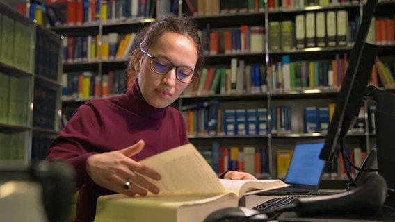 Nathalia Schomerus sitzt am Schreibtisch und liest in Büchern © NDR.de 