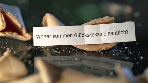 Zerbrochener Glückskeks mit einem Zettel und der Aufschrift: "Woher kommen Glückskekse eigentlich?" © NDR.de 