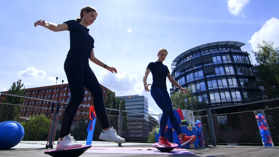 Physiotherapeutin Svea Köhlmoos und Patientin halten einbeinig auf Balancebrettern das Gleichgewicht. © NDR 