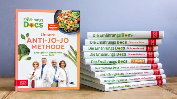Viele Bücher der Ernährungs-Docs liegen gestapelt auf einem Tisch, daneben steht das neueste Buch. © NDR/ZS Verlag Foto: Claudia Timmann