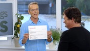 Dr. Matthias Riedl zeigt seiner Patientin ein Blatt Papier - die schaut weg. © NDR/Moritz Schwarz 