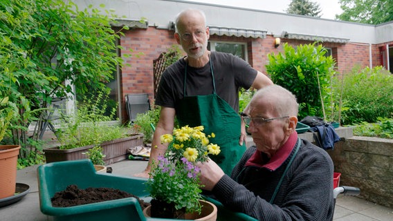 Gartentherapeut Thomas Hentschel bepflanzt mit Hospiz-Gast Ralf Löwenhagen eine Schale für seine Terrasse. So hat der 62-Jährige jeden Tag eine Aufgabe. © NDR/Axel Schneppat 