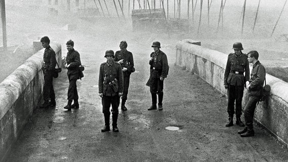 Kurz vor Ende des Zweiten Weltkriegs erhalten die unbedarften Oberschüler Hans Scholten (Folker Bohnet), Albert Mutz (Fritz Wepper), Walter Forst (Michael Hinz), Jürgen Borchert (Frank Glaubrecht), Klaus Hager (Volker Lechtenbrink), Sigi Bernhard (Günther Hoffmann) und Karl Horber (Karl Michael Balzer) den militärisch sinnlosen Auftrag, eine Brücke in ihrem Heimatort zu verteidigen. © ARD Degeto 