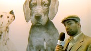 Reporter Mehmet vor Hundeplakat  