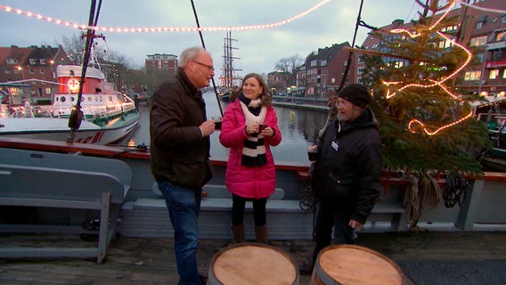 Jakob Oltmanns und Norbert Rau zeigen Heike Götz einen alten Heringslogger in Emden. © NDR 