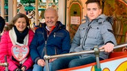 Hans Dieter Kruse und Sohn Jonas zeigen Heike Götz ihr altes Pferdekarussell auf dem Auricher Weihnachtsmarkt. © NDR/Matthias Adelmund 