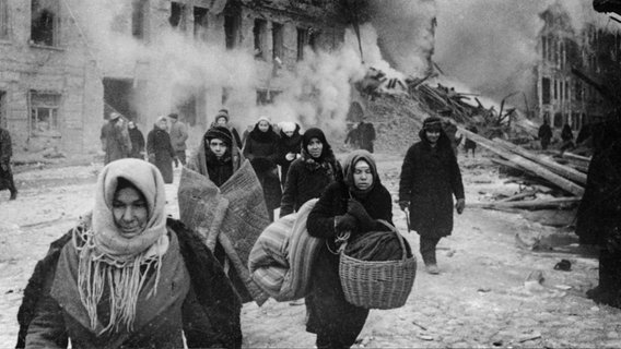 Im belagerten Leningrad läuft eine Gruppe von Frauen zwischen zerbombten Häusern. © picture alliance/ akg-images 