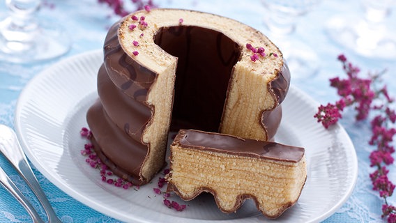 Ein angeschnittener Baumkuchen liegt auf einem weißen Teller. © fotolia.com Foto: victoria p.