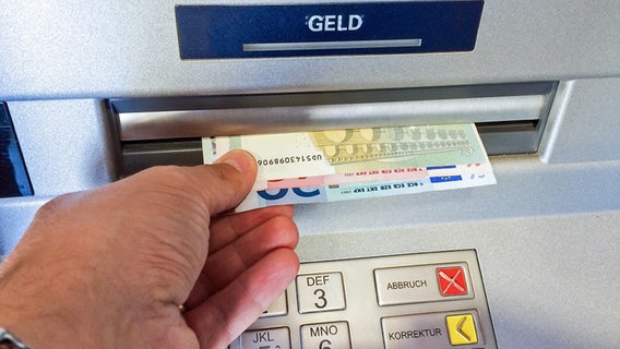 Eine Männerhand nimmt Geld aus dem Geldautomat. © fotolia Foto: Jürgen Fälchle