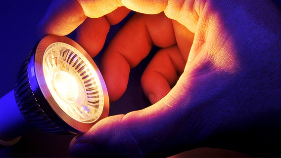 Eine Hand umfasst eine leuchtende Led-Lampe © Fotolia.com Foto: demarco