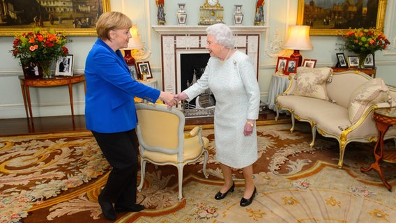 Königin Elizabeth begrüßt am 27. Februar 2014 Angela Merkel per Handschlag in einem nobel ausgestatteten Kaminzimmer. © picture alliance / dpa Foto: Dominic Lipinski / Pa Wire