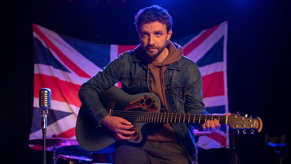 Verborgene Talente: Kommissar Gregor (Jonas Minthe) greift im Klub des verdächtigen englischen Betreibers Philip Yates zur Gitarre. © ARD/Thorsten Jander 