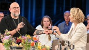 Der Hypnotiseur, "Wundermacher" und Autor Jan Becker hält in der NDR Talk Show die Hand der Schauspielerin Juliane Köhler und beide halten in der jeweils anderen Hand ein Smartphone. © NDR Fernsehen/ Uwe Ernst Foto: Uwe Ernst