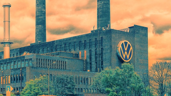 Das Heizkraftwerk von VW in Wolfsburg - Backstein-Gebäude mit hohen Schornsteinen und großem VW-Logo an der Front. Aufnahme vom gegenüberliegenden Ufer des Mittellandkanals. Bild ist zweifarbig verfremdet. Orange (Himmel) und Petrol (Gebäude). © picture alliance / Daniel Kalker Foto: Daniel Kalker