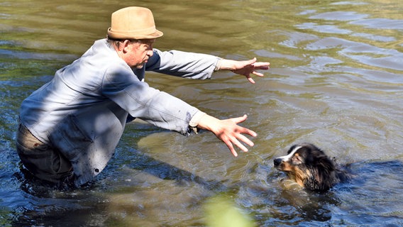 Szenenbild aus der 85. Büttenwarder-Folge "Verdammter Hund": Adsche und ein Hund sind im Dorfteich. © NDR/Nico Maack Foto: Nico Maack