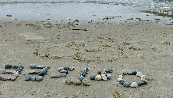 Steine am Strand bilden das Wort "Ostsee". © NDR Foto: Den Lisa Pegel aus Erkner