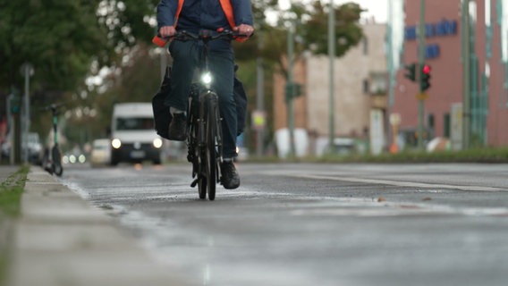 Ein Fahrradfahrer auf einer Straße, im Hintergrund Autos. © NDR 