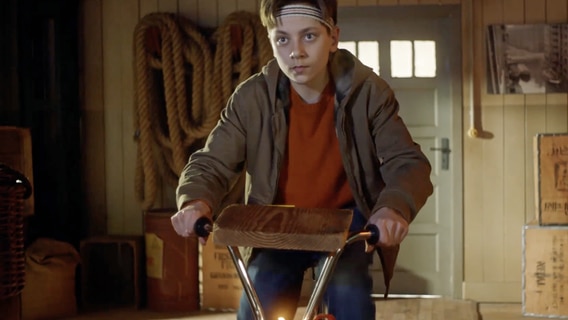 Moritz sitzt mit einem Schweißband auf dem Kopf auf einem umgebauten Fahrrad, um damit Strom zu erzeugen. © NDR/Letterbox 