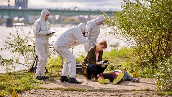 Dr. Schmidt (Helene Grass, r.) weist die Kollegen (Komparsen) in den Tatort ein. © NDR/ARD/Frank Dicks 